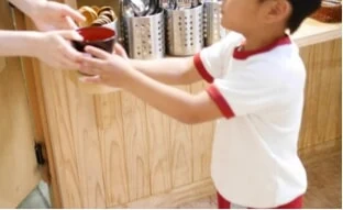こども食堂で食事を受け取る子ども